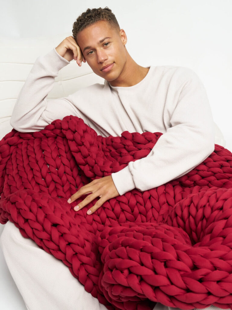 Person resting comfortably on couch under Comfrt CuddleCloud weighted blanket